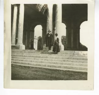 photographie d'André Gide, avec chapeau et cape, et Élisabeth Van Rysselberghe, enceinte de Catherine Gide, debout sur l’escalier d’un monument, janvier-février 1923