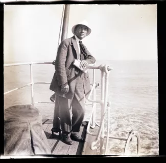photographie d'André Gide, accoudé sur le pont du bateau qui l'emmène en Corse avec André Allégret et Élisabeth Van Rysselberghe, août 1923