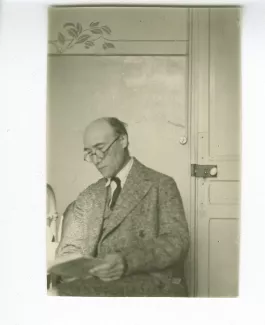photographie d’André Gide, assis, lisant près d’une porte, à l'hôtel Maritima, printemps 1925