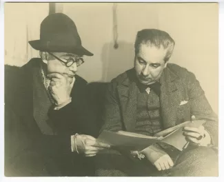 photographie d’André Gide, avec chapeau, et Roger Martin du Gard, relisant ensemble une dactylographie de manuscrit