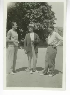 photographie d’André Gide, avec chapeau, fumant, entouré du boxeur Billy Balzac, à gauche, et de Sam Quinchon, à droite, 30 août 1930