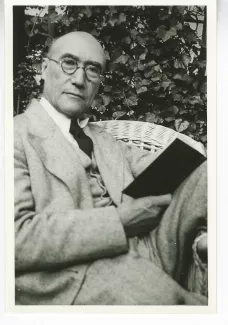 portrait photographique d'André Gide, de face, tête inclinée vers la droite, un livre dans la main droite, mai 1930