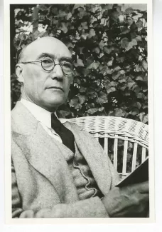 portrait photographique d'André Gide, de ¾ face, la tête légèrement renversée, la main droite tenant un livre, mai 1930