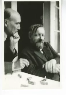 photographie d'André Gide, de profil, fumant, main gauche sur la joue, et Bernard Groethuysen, cigarette en bouche, tous deux souriant, juillet 1931