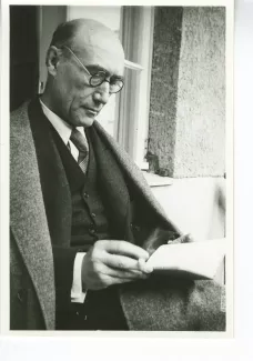 portrait photographique d'André Gide, avec lunettes, lisant, cigarette dans la main droite, juillet 1931