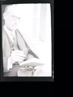 portrait photographique d'André Gide, avec lunettes, lisant, cigarette dans la main droite, juillet 1931