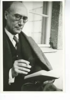 portrait photographique d'André Gide, avec lunettes, lisant, cigarette dans la main droite, juillet 1931