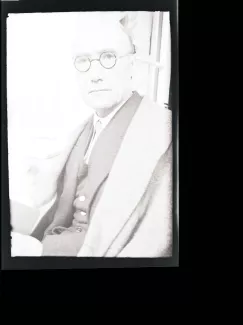 portrait photographique en buste d'André Gide, regardant l'objectif, avec lunettes, main droite floue, juillet 1931