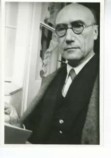 portrait photographique en buste d'André Gide, regardant l'objectif, avec lunettes, main droite près d'un livre, juillet 1931