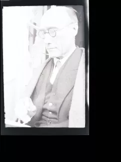 portrait photographique en buste d'André Gide, de ¾ gauche, avec lunettes, lisant et fumant, juillet 1931