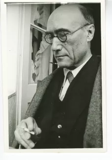 portrait photographique en buste d'André Gide, de ¾ gauche, avec lunettes, lisant et fumant, juillet 1931