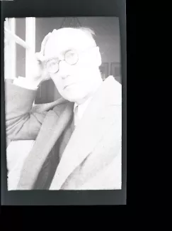 portrait photographique en buste d'André Gide, avec lunettes, la main droite sur le crâne, regardant l'objectif, juillet 1931