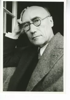 portrait photographique en buste d'André Gide, avec lunettes, la main droite sur le crâne, regardant l'objectif, juillet 1931