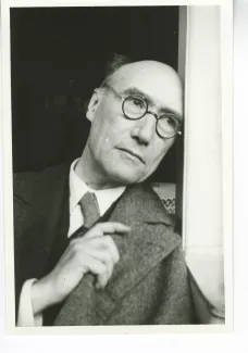 portrait photographique en buste d'André Gide, avec lunettes, la tête reposant sur l'encadrement de fenêtre, la main droite sur le col du manteau, juillet 1931