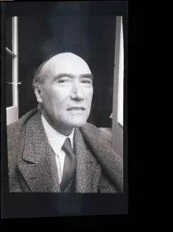 portrait photographique en buste d'André Gide, presque de face, regarde l’objectif avec un sourire forcé, juillet 1931