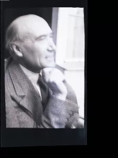 portrait photographique en buste d'André Gide, presque de profil, souriant, poing droit sous le menton, juillet 1931