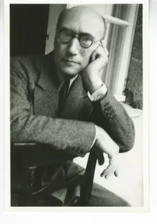 portrait photographique d'André Gide, avec lunettes, la main gauche sur la joue, à califourchon sur une chaise, juilet 1931