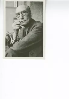 portrait photographique en buste d'André Gide, avec lunettes, regardant l'objectif, cigarette dans la main droite, le coude droit posé sur le genou, juillet 1931