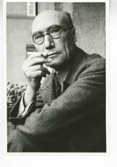 portrait photographique en buste d'André Gide, avec lunettes, regardant l'objectif, cigarette dans la main droite, le coude droit posé sur le genou, juillet 1931