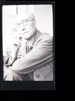 portrait photographique en buste d'André Gide, avec lunettes, regardant l'objectif, cigarette dans la main droite, le coude droit posé sur le genou, juillet 1931