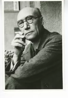 portrait photographique en buste d'André Gide, avec lunettes, regardant l'objectif, cigarette dans la main droite, le coude droit posé sur le genou, juillet 1931