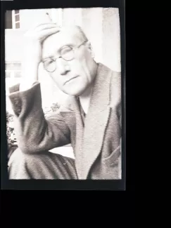 portrait photographique en buste d'André Gide, avec lunettes, regardant l'objectif, la main droite avec cigarette sur le front, juillet 1931