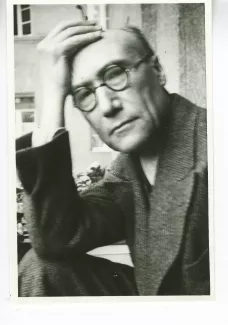 portrait photographique en buste d'André Gide, avec lunettes, regardant l'objectif, la main droite avec cigarette sur le front, juillet 1931