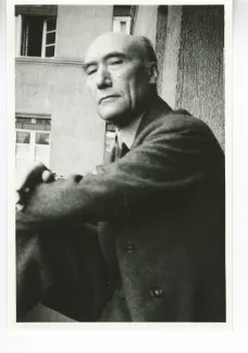 portrait photographique d'André Gide, regardant l'objectif de haut, cigarette dans la main droite, le bras gauche posé sur le genou droit, juillet 1931