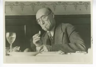 photographie d’André Gide, allumant une cigarette, lors d’un déjeuner à La Crochette, 9 décembre 1933