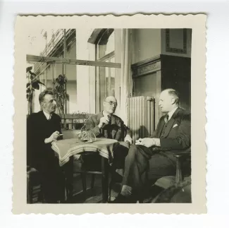 photographie d’André Gide, attablé, et deux Bellettriens, dont Daniel Simond à gauche, dans un restaurant, décembre 1933