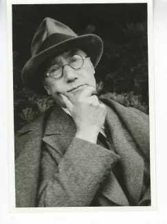 portrait photographique en buste d'André Gide, avec lunettes et chapeau, de face, la main droite sur le menton, songeur, août 1934