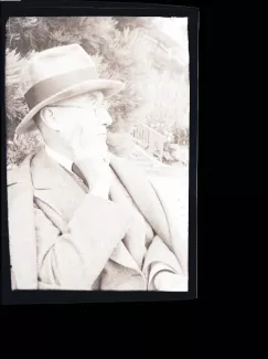 portrait photographique en buste d'André Gide, avec lunettes et chapeau, de profil droit, la main droite soutenant son menton, août 1934