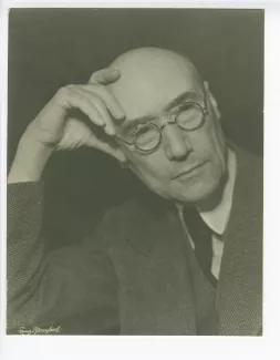 portrait photographique en buste d’André Gide, avec lunettes, la main droite soutenant sa tête, août 1934