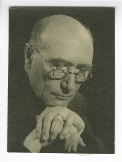 portrait photographique en buste d’André Gide, avec lunettes, la tête inclinée, le menton posé sur le dos de ses mains