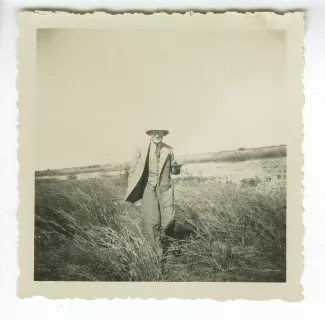 photographie d’André Gide, avec lunettes et casque colonial, souriant, debout dans la brousse, février-avril 1936