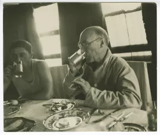 photographie d’André Gide, avec lunettes, et Eugène Dabit, buvant tous deux, attablés pour le petit-déjeuner sur un bateau lors du voyage en URSS, juilet-août 1936