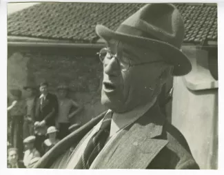photographie d’André Gide, avec lunettes et chapeau, chantant devant la foule, lors de l'inauguration du boulevard Maxime-Gorki à Villejuif, 29 juin 1935