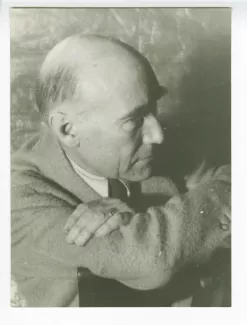 portrait photographique en buste d’André Gide, de profil à droite, les coudes sur le dossier d'une chaise