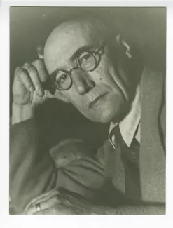 portrait photographique en gros plan d’André Gide, avec lunettes, regardant l’objectif, la tête appuyée sur la main droite