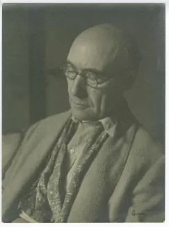 portrait photographique en buste d’André Gide, avec lunettes et foulard fleuri, de ¾ à gauche, lisant, au Vaneau