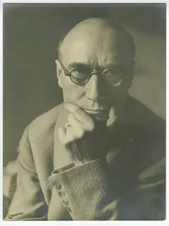 portrait photographique en buste d’André Gide, avec lunettes, de face, regardant l’objectif, la main gauche sur le menton, au Vaneau