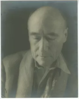 portrait photographique en gros plan d’André Gide, avec foulard fleuri, de face, regardant vers le bas, au Vaneau