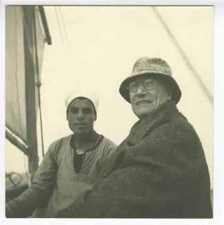 photographie d’André Gide, avec chapeau et lunettes, souriant à l’objectif, et un jeune Egyptien, sur un bateau, mars 1939