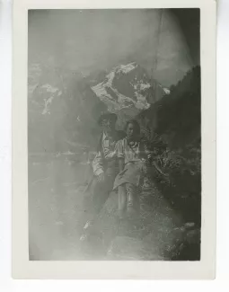 photographie d’André Gide, avec chapeau et lunettes, et Catherine Gide, assis sur un rocher, devant un paysage de montagnes, juillet 1935