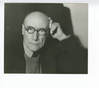 portrait photographique en buste d’André Gide, avec lunettes, la main gauche contre la tête, mars 1944