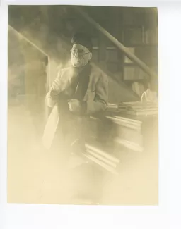 portrait photographique d’André Gide, avec lunettes et bonnet, accoudé à son piano, fumant, au Vaneau