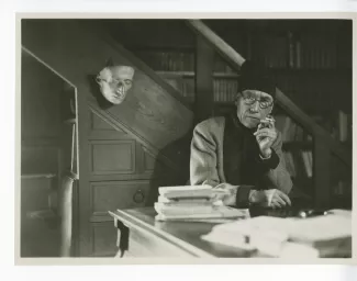 portrait photographique d’André Gide, avec lunettes et bonnet, accoudé à son piano, de face, fumant, au Vaneau
