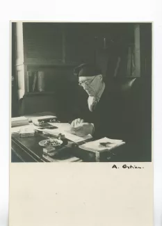 portrait photographique d’André Gide, avec lunettes et bonnet, assis à son bureau, lisant, au Vaneau