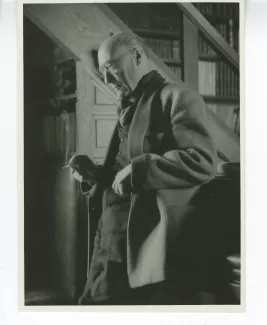 portrait photographique d’André Gide, avec lunettes, debout, adossé à son piano, au Vaneau, été 1946