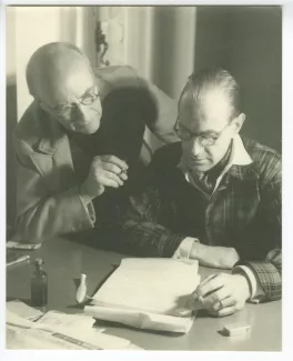 photographie d’André Gide, avec lunettes, et Richard Heyd, lisant ensemble un manuscrit, chez l'éditeur